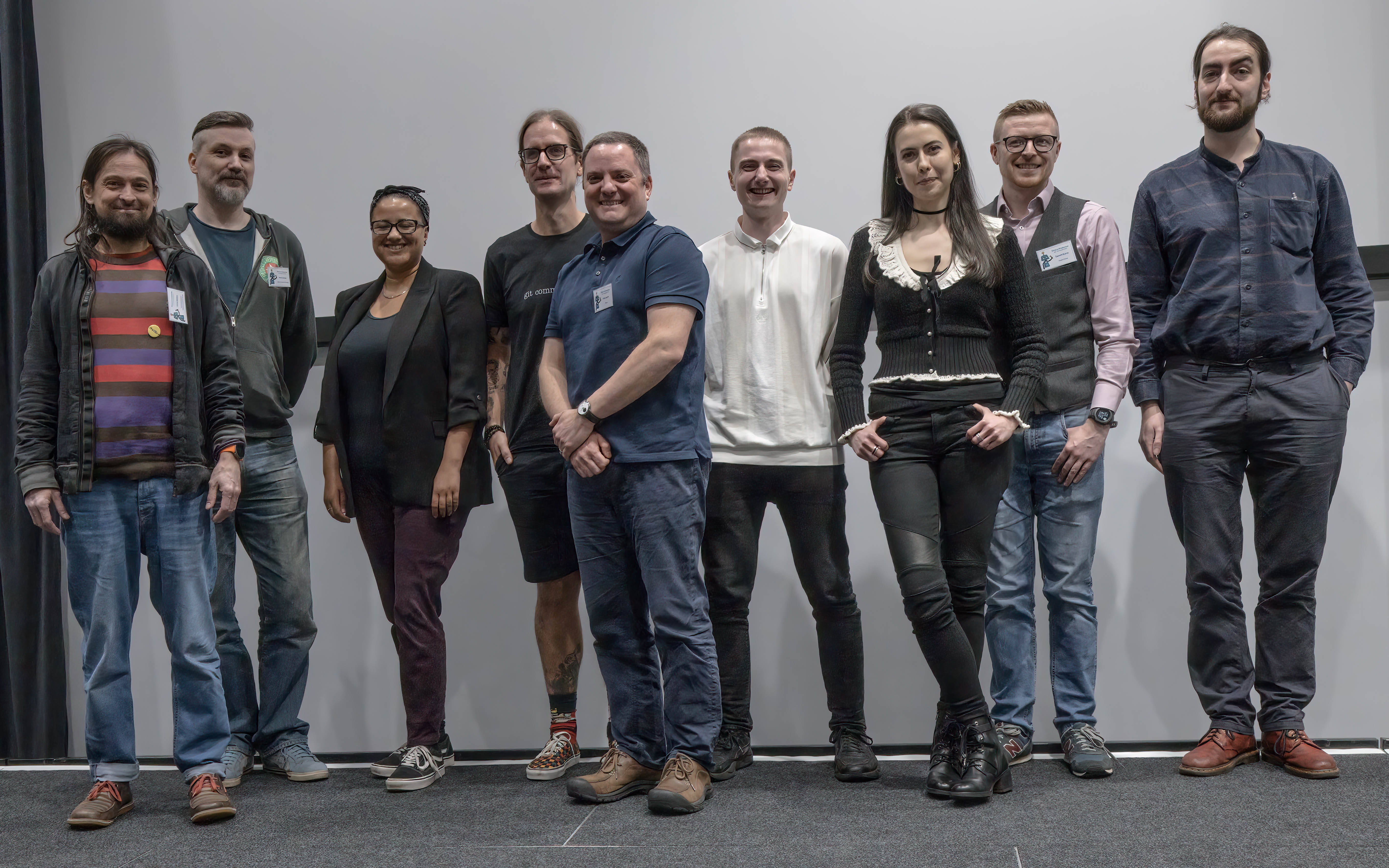 Speakers grouped together on stage at the conference. Left to right: Chris Beeley, Mark Sellors, Nic Crane, Colin Fay, Mike Smith, Theo Roe, Caterina Constantinescu, Gareth Burns, Andrew Patterson